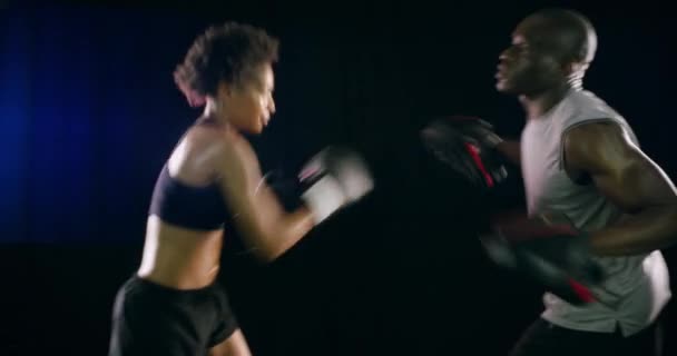 ボクシング 健康のための暗い背景にスタジオで黒いカップルとのフィットネスのために戦います 運動トレーニングやトレーニングで男女のボクサーとの戦い 自己防衛またはスパイリング — ストック動画