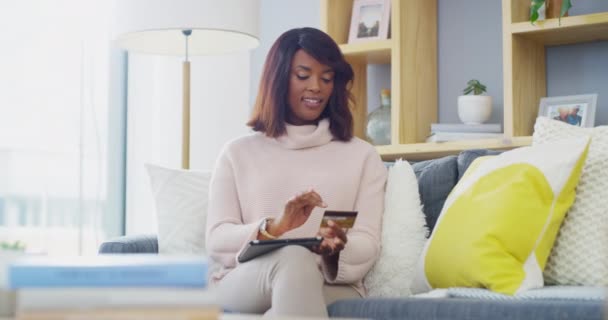 ブラック女性 クレジットカード イエス オンラインショッピング Eコマース インターネットでの購入 リビングルーム テクニカル決済 モチベーションとソファーのバンキングアプリの成功に満足 — ストック動画