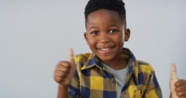 Mutlu çocuk, başarılı ol ve kazan, başarılı ol ya da stüdyo geçmişine karşı iyi iş çıkar. Heyecanlı Afrikalı küçük çocuk gülümsemesinin portresi emoji gibi görünüyor, evet işareti ya da tamamdır..