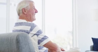Yüzü, komik ve yaşlı bir adam, evdeki oturma odasındaki kanepede emeklilik için düşünüyor ve heyecanlanıyor. Portre, kanepede oturan yaşlı insan ve gülmek sağlığa, sağlığa ve evdeki rahatlığa gülümse..