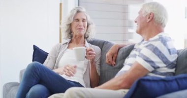 Kahve, sohbet ve kanepede oturan yaşlı çift birlikte emekliliklerinin tadını çıkarıyorlar. Aşk, konuşma ve oturma odasında çay, iletişim ve hafta sonu özgürlüğü olan yaşlı insanlar..