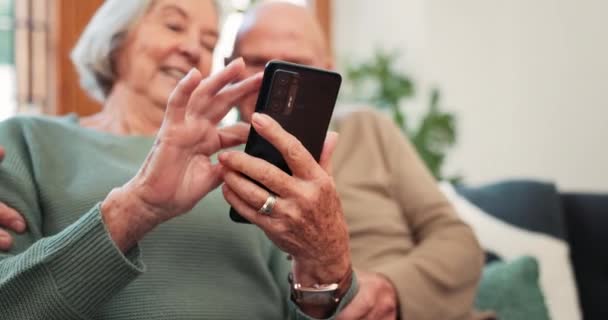 自宅の手 シニアカップル スマートフォンは オンラインでスクロールし ソファで通知やニュースアプリを読みます クローズアップ パーキンソンが携帯電話 ソーシャルメディア モバイルコンタクトでタイピングする老人と女性 — ストック動画