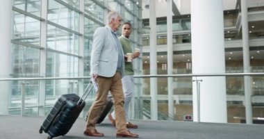 Havaalanı, seyahat ve iş adamları uluslararası bir uçuş için bir terminalde bavulla yürüyorlar. İş birliği, çeşitlilik ve seyahat için bavul tutarken çalışanıyla konuşan bir akıl hocası..