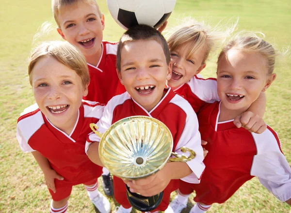 Children, soccer team and portrait with cup, boys and girls with victory, support or solidarity. Achievement, sports and friendship, together and happy for win, ready for game or physical activity.