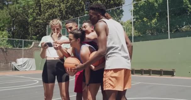 バスケットボール 友人と裁判所で一緒に ソーシャルメディアで面白いミームやビデオを見てください スマートフォン スポーツ 幸せな人のグループは 夏に屋外でコメディ ジョーク フィットネスアプリで笑います — ストック動画