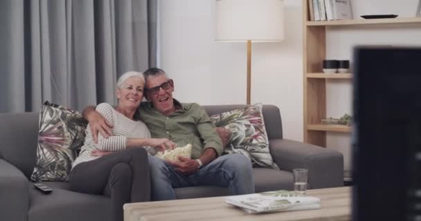ソファーで映画 ポップコーン シニアカップル リラックス ボンディング 自宅で一緒にショーを見ています ハッピー 高齢者と退職後の女性 家でのリビングルームで映画やビデオをストリーミング — ストック動画