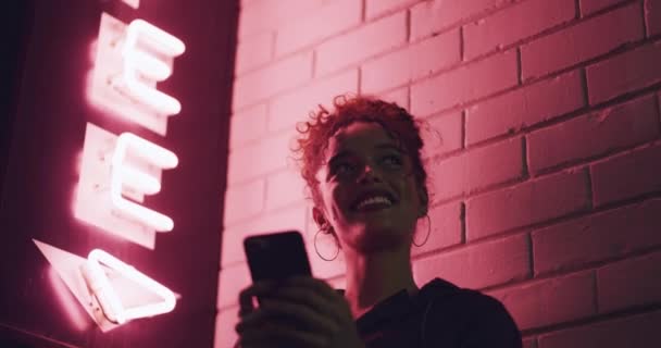 霓虹灯墙和快乐的女人 智能手机用户或在社交媒体应用程序上输入网上搜索的人 粉色的光芒 夜总会的标志和派对的女孩想到室外的手机连接 — 图库视频影像