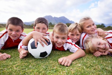 Çocuklar, futbol topu ve yeşil çimlerin üzerinde ya da açık hava maçı için rahatlayın, oyun. Ya da takım sporları. Çocuklar, arkadaşlar ya da futbolcular, doğadaki stadyum müsabakalarında hep birlikte gülüyorlar..