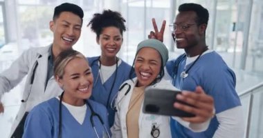 Doktorlar, ekip ve özçekim çeşitliliği ve sağlık grubu, işbirliği ve akıllı telefon fotoğrafçılığı ile mutluluk. Tıbbi profesyonel, resimde mutlu ve tıp alanında barış işareti olan insanlar..