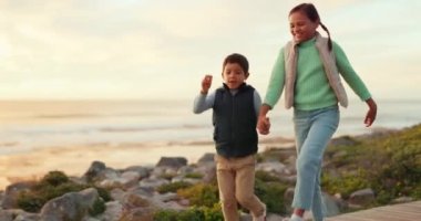 Çocuklar, el ele tutuşup sahilde macera, seyahat ya da tatil için enerji ve mutlulukla oynuyorlar. Bir erkek ve bir kız, gün batımında aile tatili için birlikte dışarı çıkmış kardeşler ya da çocuklar..