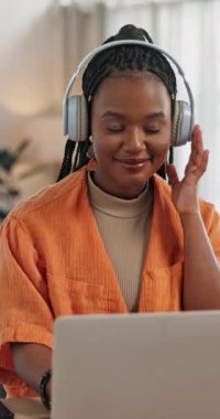 Müzik, kulaklıklar ve mutlu siyah kadın evde oturma odasında dizüstü bilgisayarda, masada ses ve ses dinliyor. Gülümse, radyo ve bilgisayar yayınındaki kişi, serbest çalışan bir işitme şarkısı ve uzaktan çalışma.