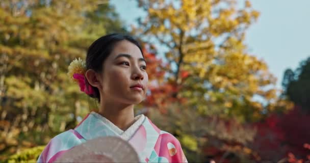 庭にいる女性 アジア人で落ち着いたファンの女性は 伝統的な服の反射と静けさで人生について考えます インスピレーションや洞察力を持つ新鮮な空気のための平和な日本公園と自然 — ストック動画