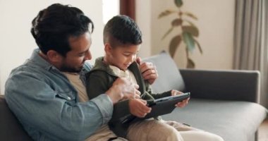 Baba, çocuk ya da oyun oynamak için evdeki kanepede bir tablet, online öğrenme ve multimedya yayını. Mutlu baba, çocuk çocuğu dijital teknolojisiyle gıdıklıyor. Çizgi film ve filmleri izleyip dinleniyor..