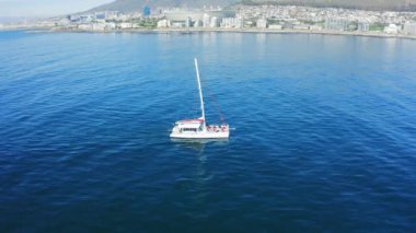 Şehir, insansız hava aracı ve tekne Cape Town 'da sahil, şehir manzarası ve dağlarla birlikte. Şehir, su ve gökyüzü manzaralı ve okyanus manzaralı ve deniz manzaralı binalar ve tatil.