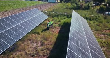 İnsansız hava aracı, mühendislik veya yenilenebilir enerji, temiz elektrik veya sürdürülebilirlik için güneş panelleri olan insanlar. Hava manzarası, çalışanlar veya fotovoltaik bir çiftlikte veya bakım işleri için açık havada.