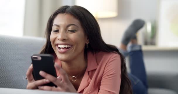 在家里用智能手机笑着打字 阅读社交媒体的帖子和沙发上有趣的联系方式 非洲人 在客厅里放松和下载数字应用 迷因或手机游戏 — 图库视频影像
