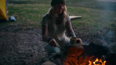 Ateş, kamp ve tatilde kızartmak için marşmelovlu bir kadın ve çadırda açık hava macerası. Seyahat, gece ve şenlik ateşinin yanında doğa yürüyüşü için tatlı, şeker ya da tatlı getiren mutlu insan..