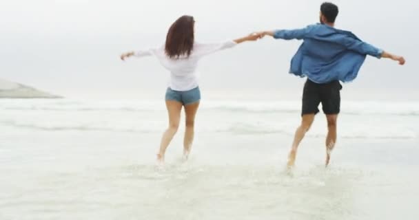手牵着手 夫妻一起奔跑 在大自然中欢庆自由与水的飞溅 爱和兴奋的人们在巴厘岛的海洋中旋转 去旅行 联系或探险 — 图库视频影像