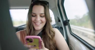 Mutlu kadın, telefon ve sosyal medya seyahat, iletişim ya da ulaşım ağları için arabada. Araçtaki kadın akıllı telefondan gülümseyerek çevrimiçi sohbet, mesajlaşma ya da yol gezisi yapıyor.