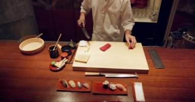 Suşi, balık ve yakın plan aşçı elleri akşam yemeğinde, mutfakta ya da restoranda yemek pişirir. Mutfak, bıçak ve yakınlaştırma sanatçısı garsonluk işinde gurme Japon yemeği ya da atıştırmalık bir şeyler hazırlıyor.