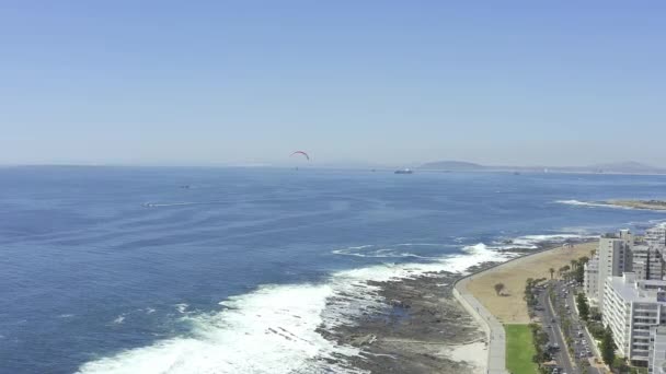 屋外の自然の中で飛ぶパラグライダーとビーチ 海岸または海岸線の空中ドローン 都市や都市の街の上空を青空で滑っている人との海水 海岸の景色 — ストック動画