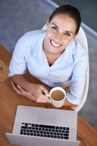Portrait, business woman and coffee at laptop for break from planning online research at desk from above. Happy employee, office worker and lady drinking tea, beverage and mug at computer in company.