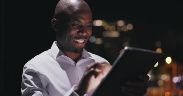 ビジネスマン タブレットにタイピング 夜や株式市場投資や市の取引のためのオンライン研究 デジタル技術 データ分析 バルコニーでのインターネット上のアフリカ人またはトレーダー — ストック動画
