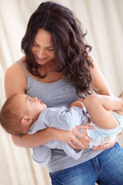 Annem bebeğini neşe dolu bir gülümsemeyle, çocuk bakımıyla ve çocuk bakımıyla evde tutuyor. Mutlu kadın, erkek bebek ve yatak odasında birlikte vakit geçirmek gelişim, güven ve anneler birbirini sever.