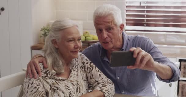ホーム ビデオ通話と高齢者のカップルと携帯電話 インターネットとの接続と朝食 話すと連絡 スマートフォン オンラインチャット デジタルアプリを持つアパート 老人または成熟した女性 — ストック動画