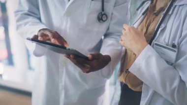 Eller, tablet ve bir grup doktor birlikte araştırma ve online danışma planlıyorlar. Dijital teknoloji, tıbbi profesyonellik ve uygulamadan sağlık hizmetleri toplantısına yakın çekim.