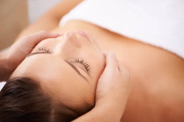 Space, woman and face massage for skincare, holistic therapy or healthy healing at cosmetics salon. Calm client relax at wellness resort for facial reiki, acupressure or peaceful treatment for beauty.