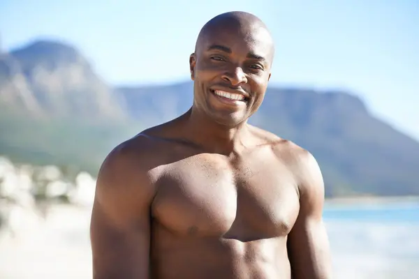 stock image Portrait of black man on beach, holiday and smile with freedom, sunshine and tropical island travel. Sea, mountain and person on ocean vacation in summer with adventure, peace and blurred background