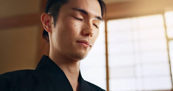 Thinking, zen and young Asian man with meditation, calm and relaxing face expression at home. Idea, mindfulness and male person with memory, reflection and breathing exercise in modern apartment