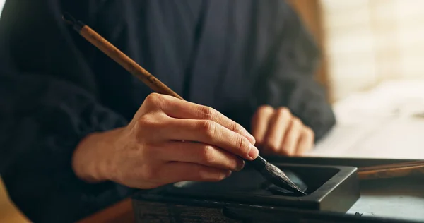 Hands, reed pen or brush in ink for writing, calligraphy or ancient script for art and inkstone. Japanese creativity, black paint and vintage tools, paintbrush and stroke, traditional and stationery.