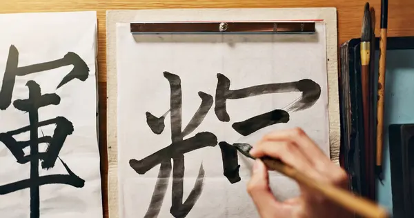 Man, calligraphy or hands of a Japanese artist in studio for art and script, letter with closeup for alphabet. Start, top or male person with tools, paintbrush and focus with traditional stationery.