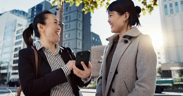 Phone, laughing and Japanese business woman in city together for travel, journey or commute. Collaboration, planning and funny with employee friends reading text message for discussion in Tokyo.