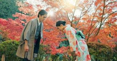 Japonya 'da parktaki insanlar selam veriyor ve geleneksel kıyafetlerini giyiyor. Doğa, güneş, saygı ve kültür. Bahçede bir çift, alçakgönüllülük ve gelenekle karşılıyorlar, kibar ve nazik..