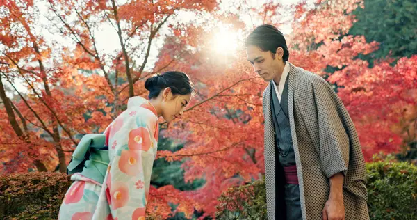 People in park in Japan, bow and traditional clothes with hello, nature and sunshine with respect and culture. Couple outdoor together in garden, greeting with modesty and tradition, polite and kind.