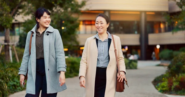 Walking, conversation and business women in the city talking for communication or bonding. Smile, discussion and professional Asian female people speaking and laughing together commuting in town