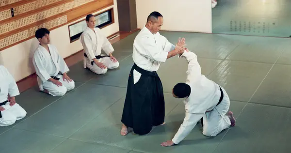 Aikido, class and fight with a master in martial arts with student in self defence, discipline and training. Technique, demonstration or Japanese sensei with black belt skill in fighting or education.