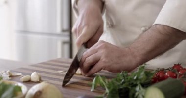Aşçı, el ve sebzeleri mutfak tezgahında yemek, sağlık ve salata hazırlamak için doğrama. İnsan, parmak ve bıçak ya da mutfak mutfağı, profesyonel ya da beceri için gemide sarımsak kesme.