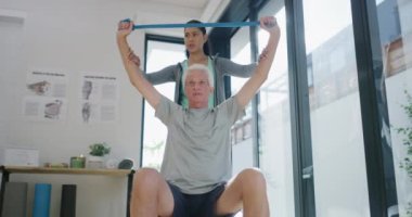 Fizyoterapist, direnç bandı ve kol rehabilitasyonu desteği, iyileştirme hizmeti ya da fizik tedavi için esneme yapan yaşlı bir adam. Emeklilik, ekipman ve sağlık çalışanı yaşlı hastalara yardım ediyor.
