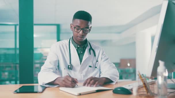 医疗保健和医生在医院的写字台上书写书籍 信息和笔记本 认真的非洲医学专业人员 杂志和研究 在桌上用电脑在纸上学习 — 图库视频影像