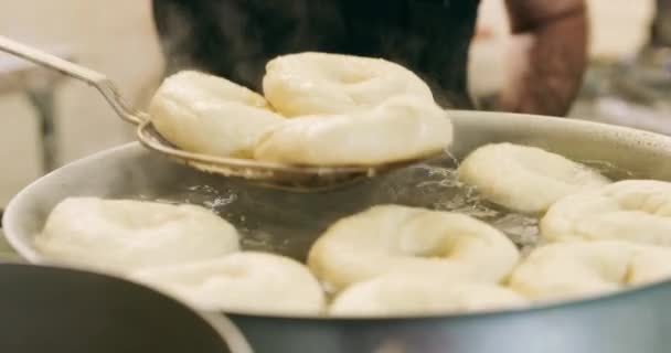 Dapur Tangan Orang Dan Saringan Dengan Bagel Dalam Panci Kompor — Stok Video