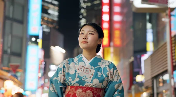 Thinking, night and Japanese woman with decision, travel and traditional clothes with wonder, relax and calm. Person, outdoor or girl in the streets, peace, commute or thoughts with culture or lights.