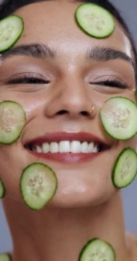 Kadın, yüz ve gülümseme salatalıkla birlikte organik tedaviye, yaşlanmayı önlemeye ya da doğal kozmetik ürünlere. Model, sebze ve detoks için dermatoloji ile mutlu, gri arka planda sağlıklı cilt ve güzellik.