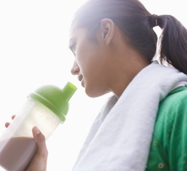 Spor, içki ve kadın. Egzersiz sonrası sağlık, sağlık ve enerji faydaları için şişede protein içeceği. Açık hava, spor sonrası beslenme için konteynırda smoothie bulunan kişi veya spordan sonra beslenme.