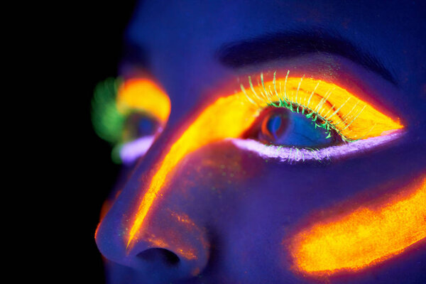 Eyes, art and creative with neon woman on black background in studio for bright vision or fantasy. Face, future and psychedelic with model in dark for galaxy or universe paint on glowing skin closeup.