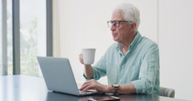 Ev bilgisayarı, kahve ve kıdemli adam araştırma hikayesi, blog ya da makale için proje fikirleri düşünüyor, merak ediyor ya da planlıyor. Çay, uzaktan çalışma veya yaşlı kişi seçimi, kararı veya problem çözme çözümünü anımsa.