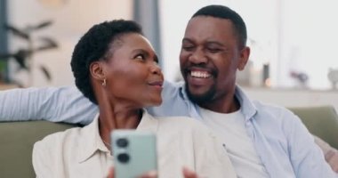 Telefon, aşk ve siyahi çift sosyal medyada bir koltukta oturuyorlar, evlerinde birlikte komik videolar izliyorlar. Akıllı telefon, gülümseme ve Afrikalı insanlar gif ya da mim uygulaması olan bir oturma odasında çevrimiçi.